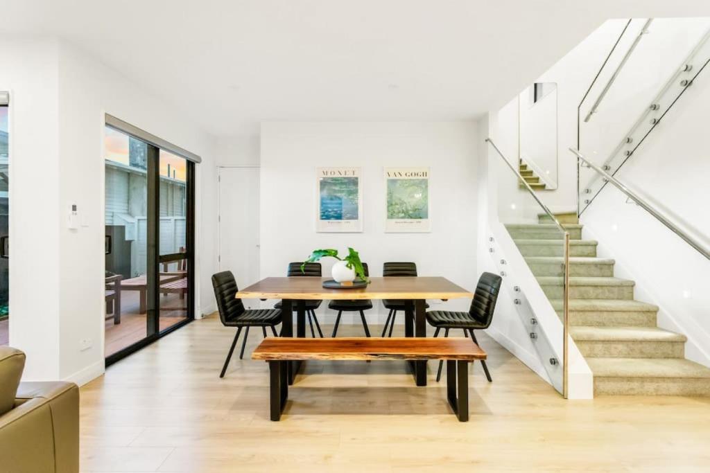 - une salle à manger avec une table, des chaises et des escaliers dans l'établissement Pristine Modern Central Home - Netflix - Heatpump, à Auckland