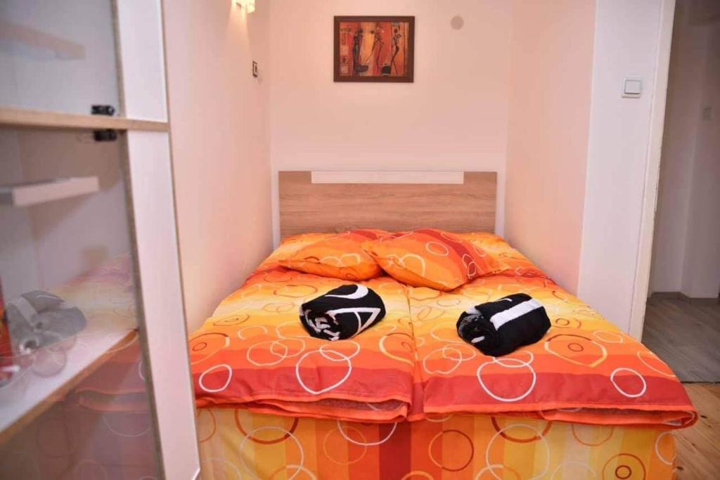 a small bedroom with a bed with an orange comforter at Ross in Veliko Tŭrnovo