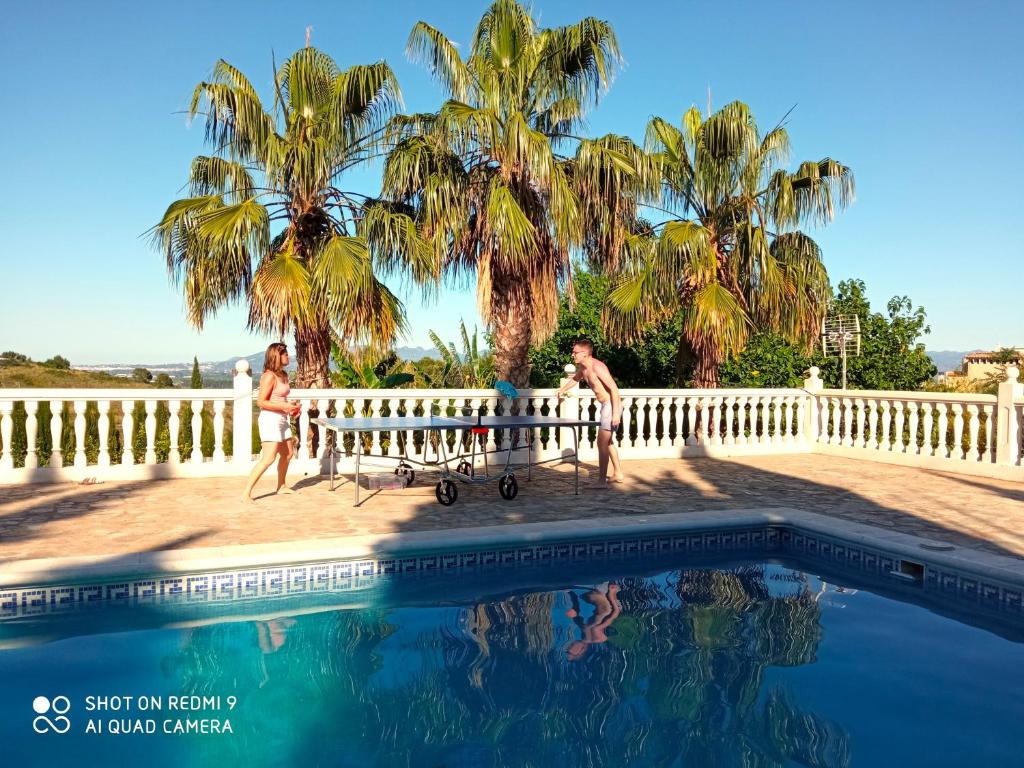 a man and a woman sitting on a bench next to a swimming pool at Las Palmeras in Alberique