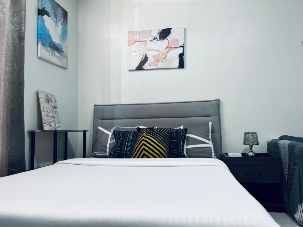 een slaapkamer met een wit bed en twee foto's aan de muur bij COZY STUDIO UNIT NEAR MACTAN AIRPORT FURNISH with WIFI, NETFLIX, POOL in Mactan