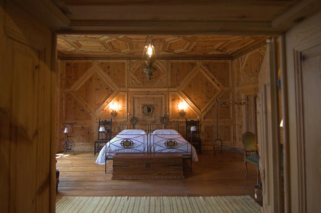 a bedroom with a bed and a wooden wall at Palazzo Juvalta in Teglio