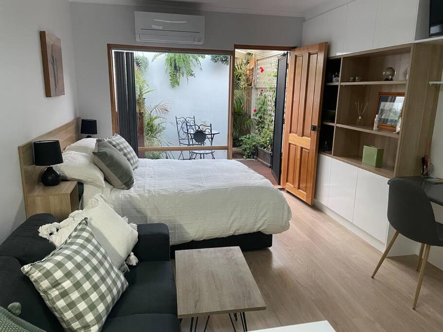 a bedroom with a bed and a living room with a couch at oasis by the beach in Glenelg