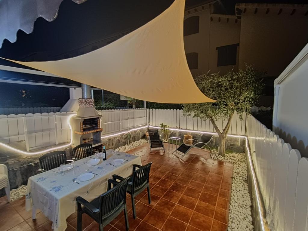 een patio met een tafel en stoelen en een open haard bij Beach House Roda de Bera in Roda de Bará