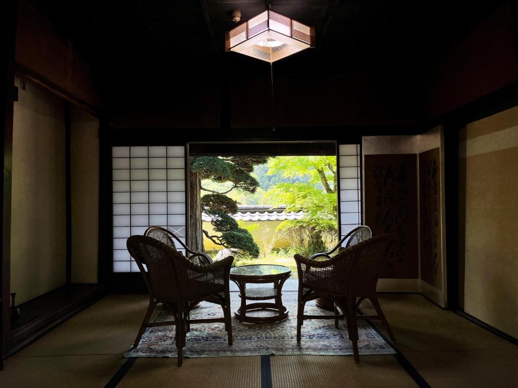 飯田市にあるゲストハウス 下瀬 アゲマツの椅子2脚、テーブル、窓が備わる客室です。