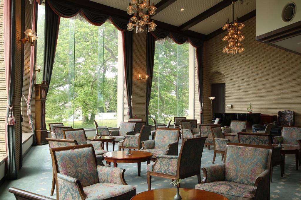 a waiting room with chairs and tables and windows at Towadako Lake View Hotel in Kosaka