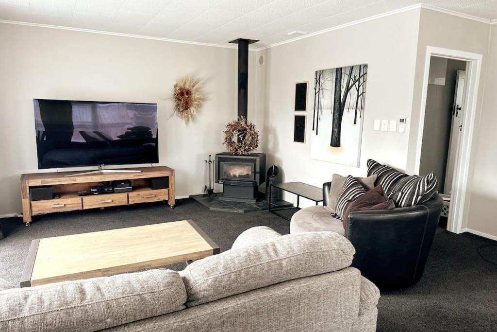 a living room with a couch and a flat screen tv at The Tirau Cottage - Waikato in Tirau