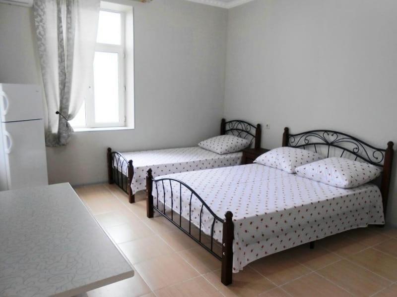 a bedroom with three beds and a window at Guest House Gorny Ruchei in Gagra