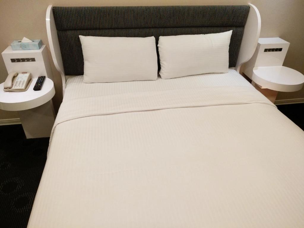 a white bed with two pillows and a telephone at Ximen Airline Hotel in Taipei