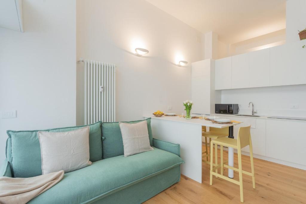 a living room with a blue couch and a kitchen at A Step from the Lake Apartment by Rent All Como in Como