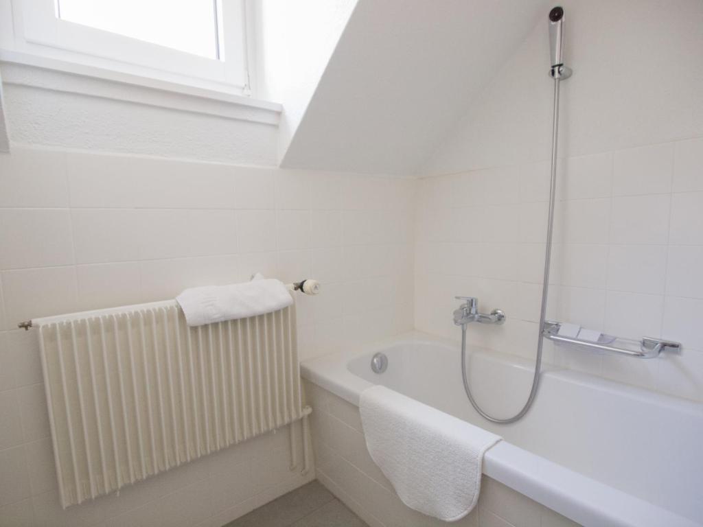 a white bathroom with a bath tub and a window at Hotel Gregory in Zürich