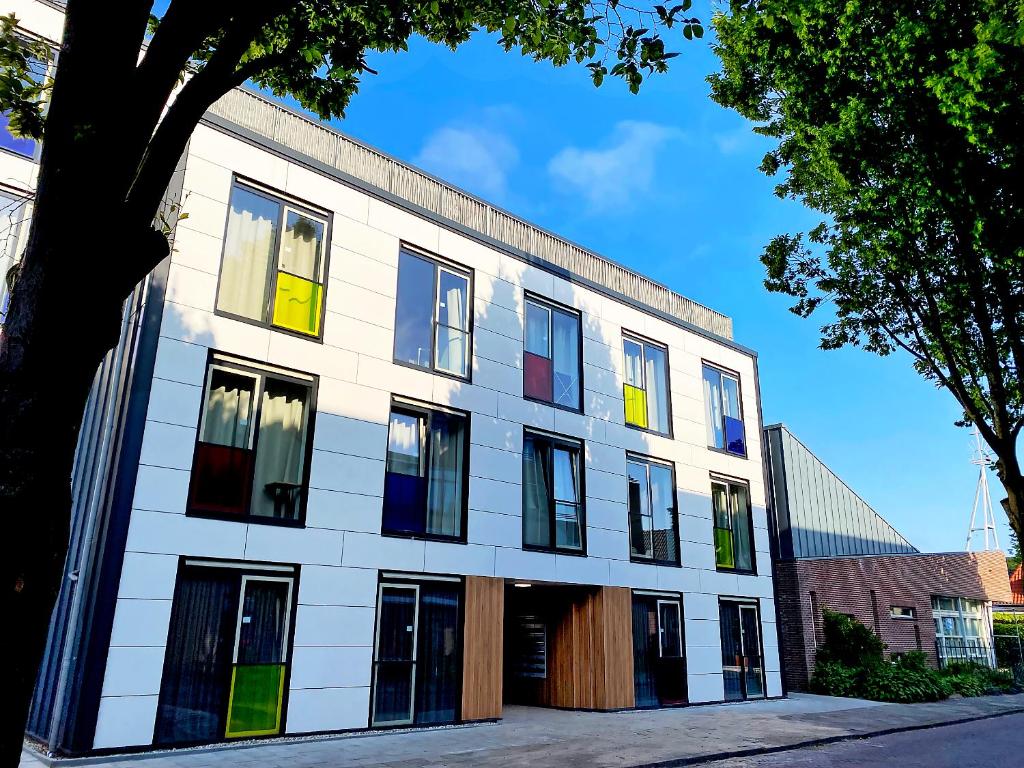 een wit gebouw met kleurrijke ramen aan een straat bij Wittenborg Student Studios in Apeldoorn