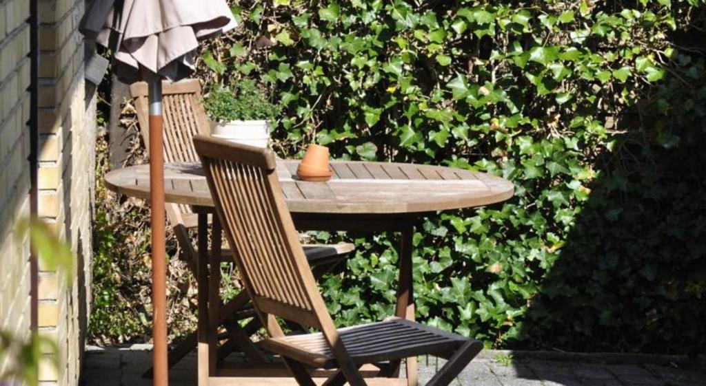 uma mesa de madeira e duas cadeiras sentadas ao lado de uma cerca em Guesthouse Højland em Ry