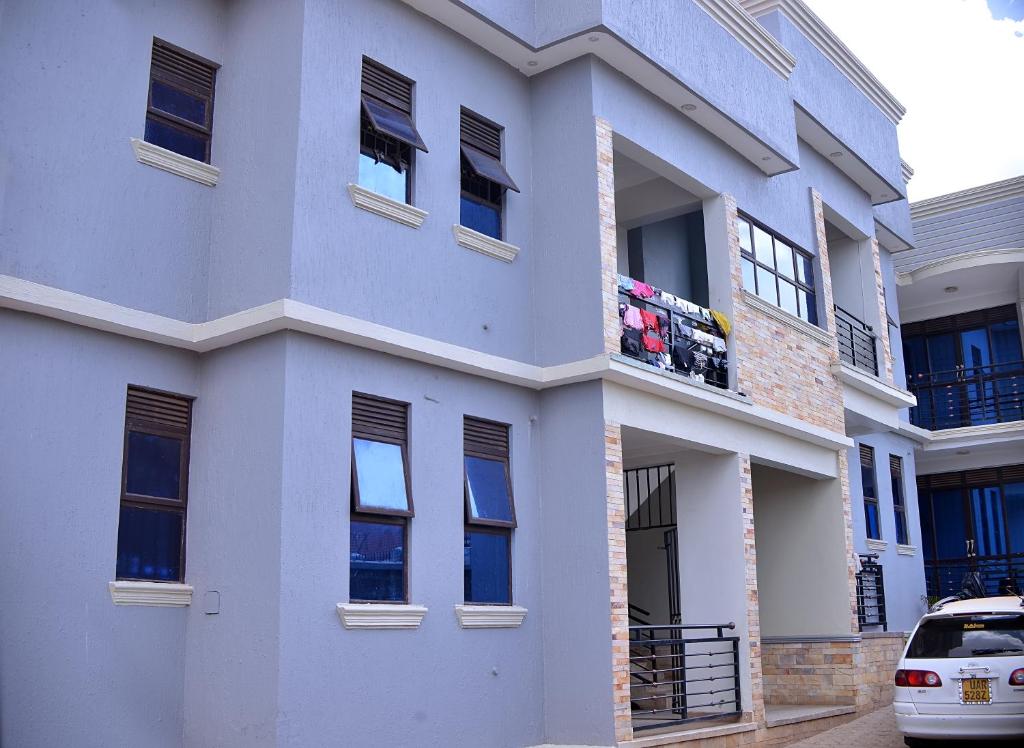 a white building with a balcony with flowers on it at Stunning 2-Bed Apartment in Namugongo Town Kampala in Kasiyirize