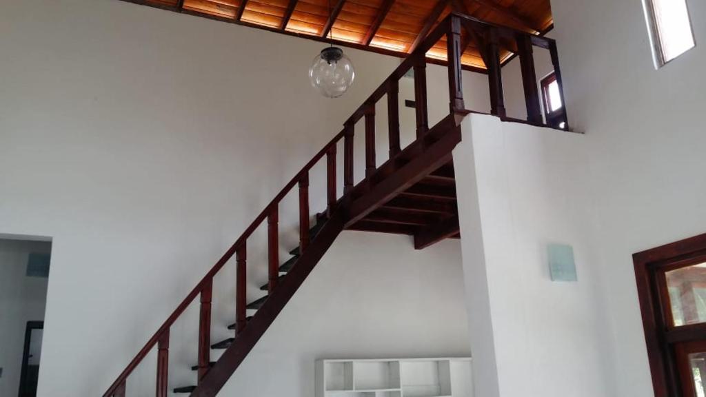 uma escada de madeira num quarto com uma parede branca em Nature View em Ranala