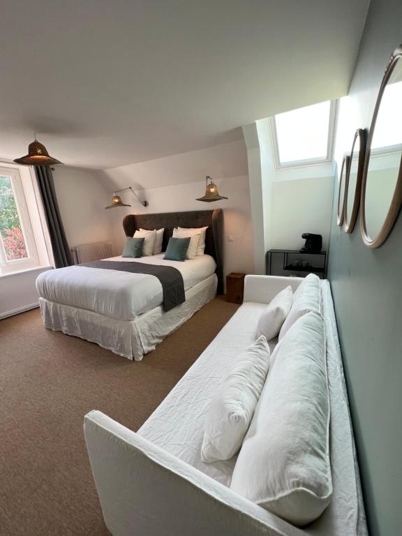 a bedroom with two beds and a couch in it at Manoir Les Feuillantines Piscine & Spa in Isques