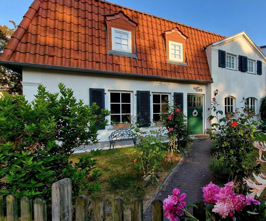una casa bianca con un tetto arancione e una recinzione di Haus mit 110qm und Garten 150m zum Wasser a Stralsund