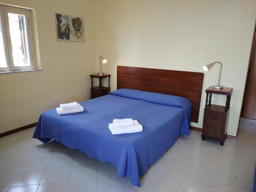 ein Schlafzimmer mit einem blauen Bett mit zwei Handtüchern darauf in der Unterkunft FORESTERIA DEL TEATRO in Agrigento