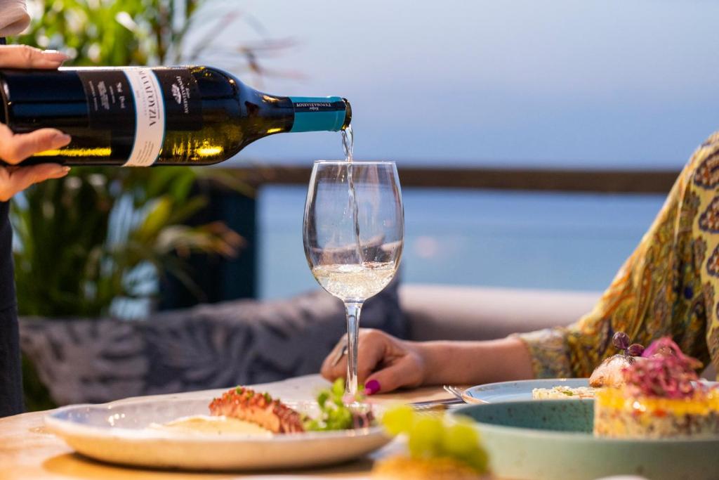 a person pouring a bottle of wine into a glass at Rigas Boutique Hotel & Spa in Afitos