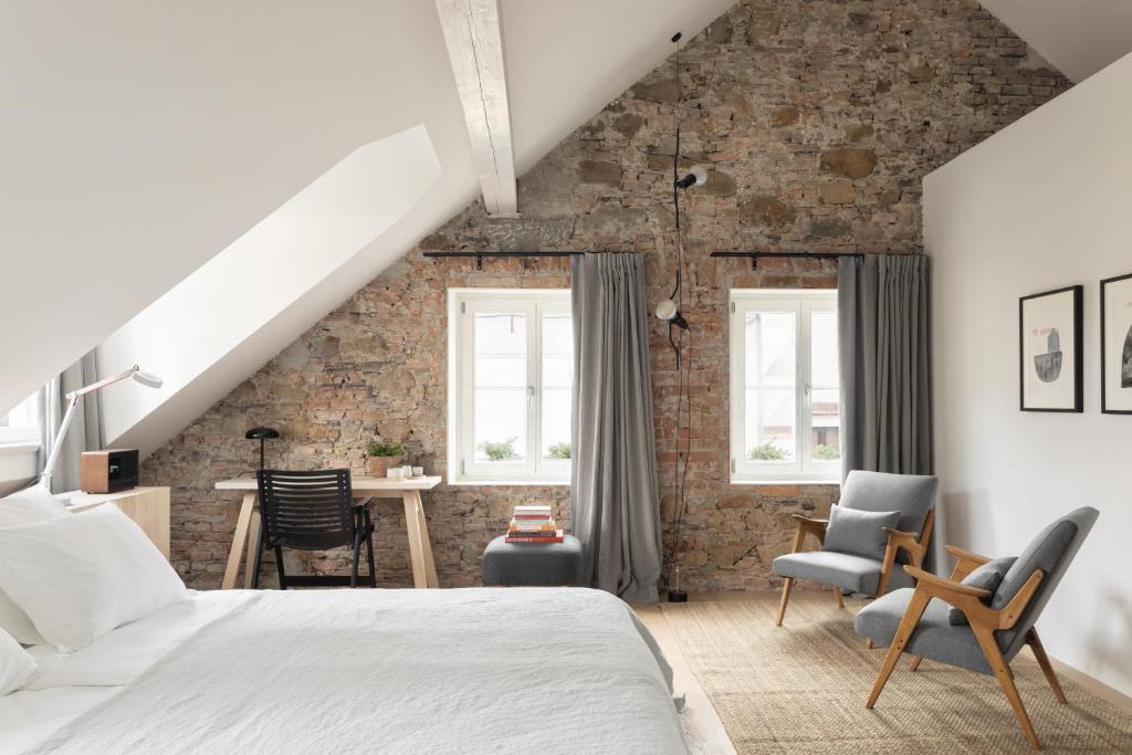 um quarto com uma cama branca e uma parede de tijolos em April1550 Boutique Hotel em Liubliana