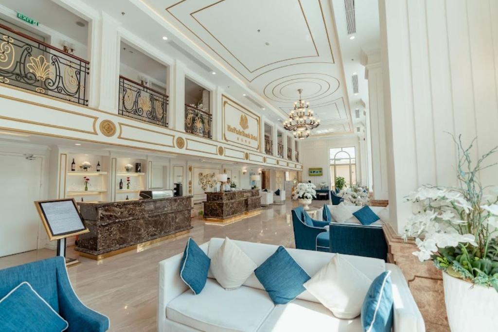 a lobby with a white couch and blue chairs at MerPerle Beach Hotel in Nha Trang