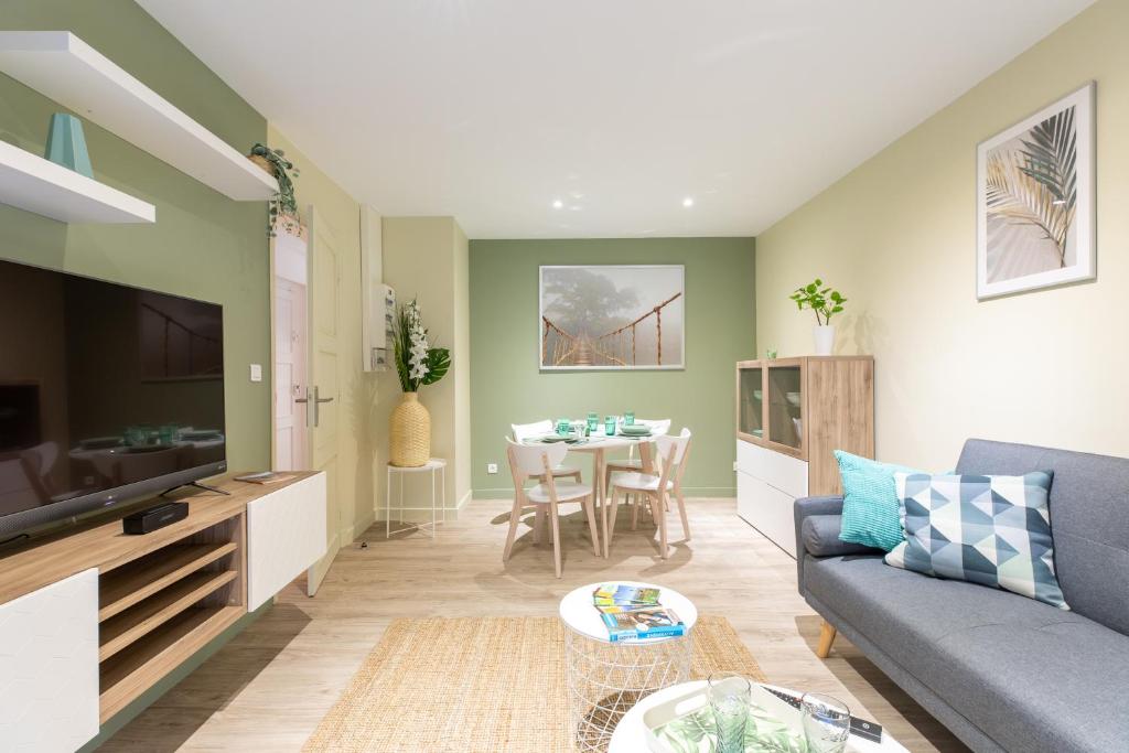 ein Wohnzimmer mit einem Sofa und einem Tisch in der Unterkunft T3 avec Terrasse & Jardin Proche de la gare Alfred Musset in Clermont-Ferrand