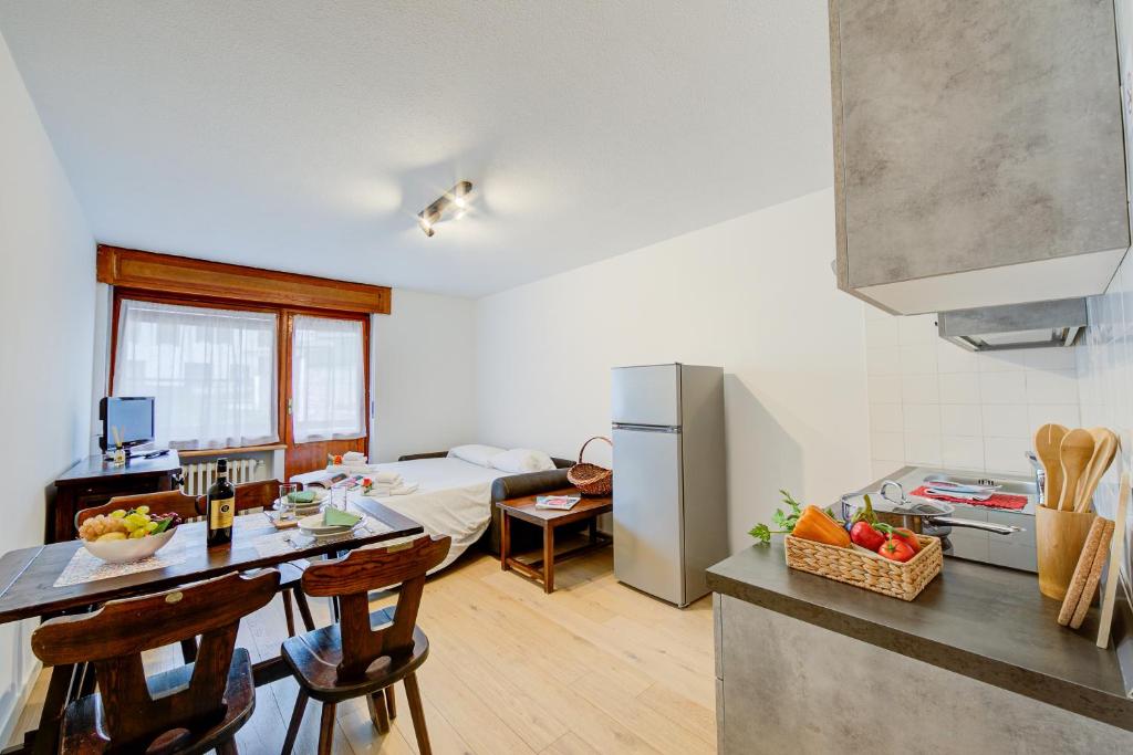 a kitchen and living room with a table and a refrigerator at Studio Genzianella Ski In-Ski Out 100m - Happy Rentals in Sestriere