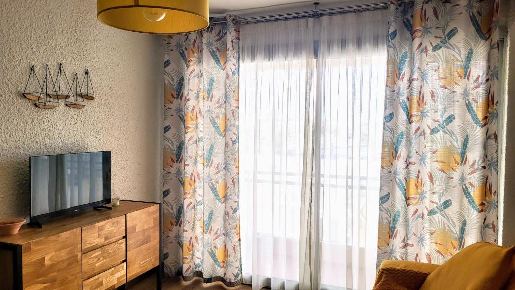 a living room with a tv and a window at Adorable petit appartement avec magnifique vue sur le port de Canet in Canet-en-Roussillon
