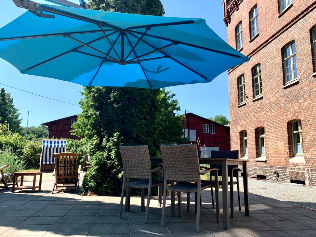een tafel met stoelen en een blauwe parasol bij Nr9Marinehafen - Ferienwohnungen in Stralsund