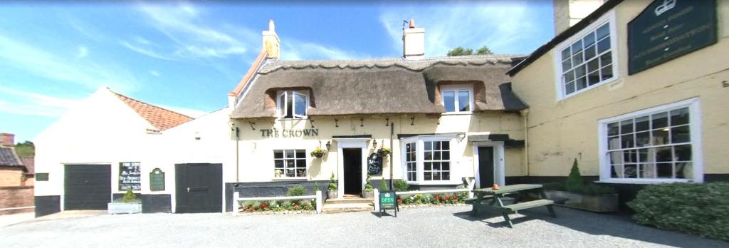 een groot wit huis met een bankje ervoor bij The Crown Inn Smallburgh in Smallburgh