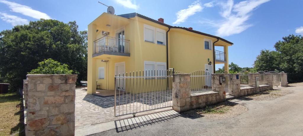 uma casa amarela com uma cerca em frente em Apartmenthaus Viktoria em Šegotići