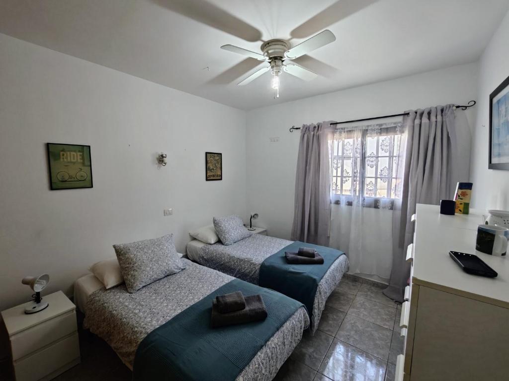 a bedroom with two beds and a couch and a ceiling fan at El Pisito La Dolce Vita in Puerto del Carmen