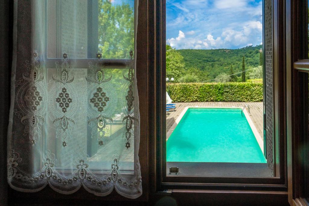 a view of a swimming pool from a window at Experience the charm of Tenuta Le Caselle, a cozy farmhouse surrounded by nature and comfort! in Subbiano