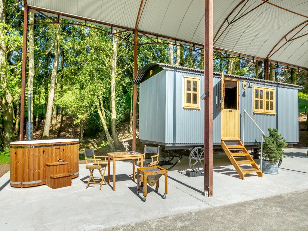 uma pequena casa azul numa tenda com uma mesa e cadeiras em Annie - Uk44003 em Cold Kirby