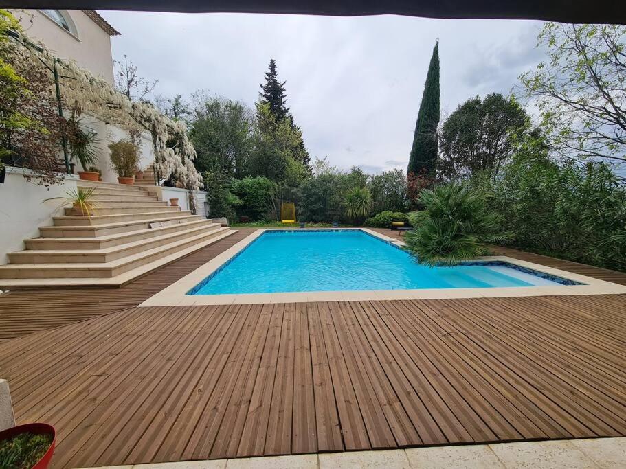 uma piscina com um deque de madeira e escadas em Villa avec vue sur Sommières em Villevieille