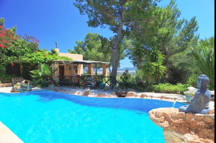 una gran piscina con una estatua junto a una casa en Villa de Montaña gran piscina, en Sant Jordi