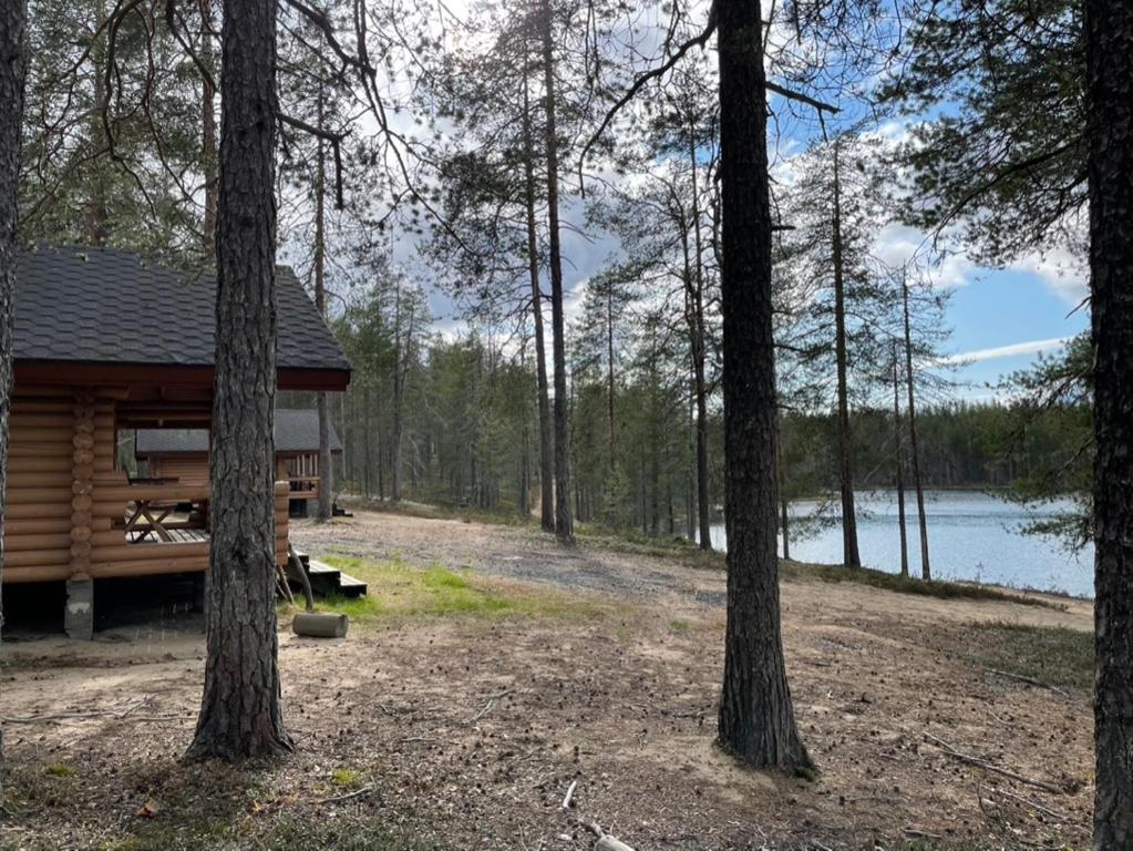 a cabin in the woods next to a lake at Kolmiloukon leirintäalue in Taivalkoski