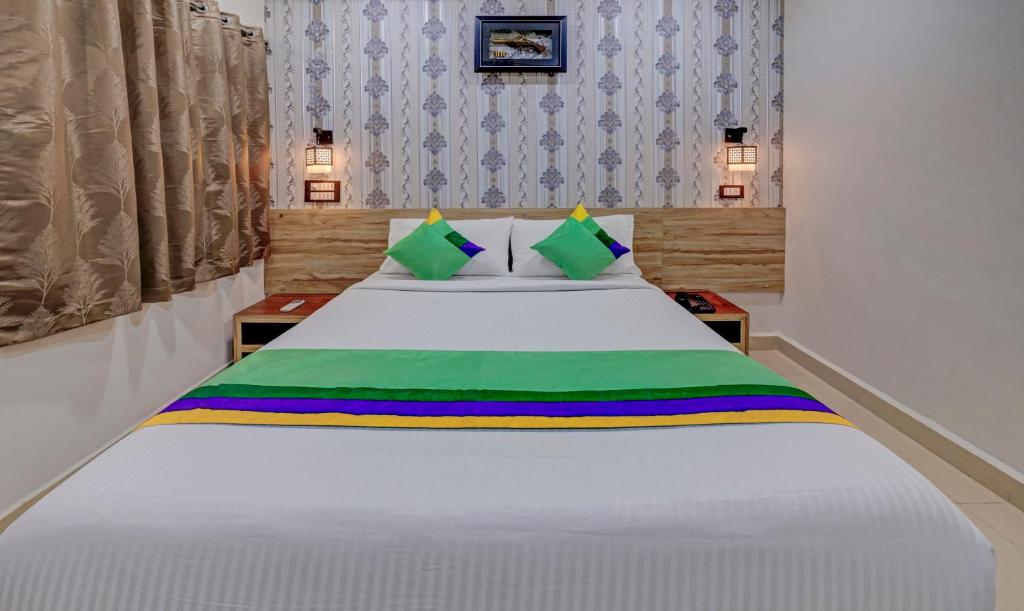 a bedroom with a white bed with green and colorful pillows at Treebo Trend Seven Inn in Tirupati