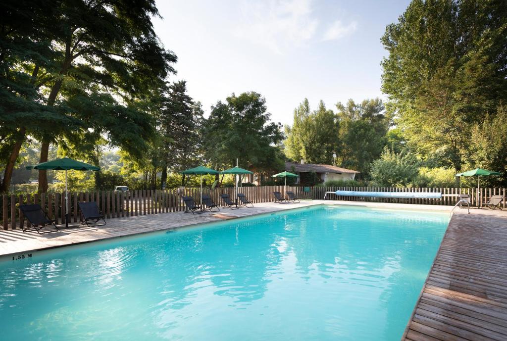 a large blue swimming pool with chairs and umbrellas at Huttopia Millau in Millau