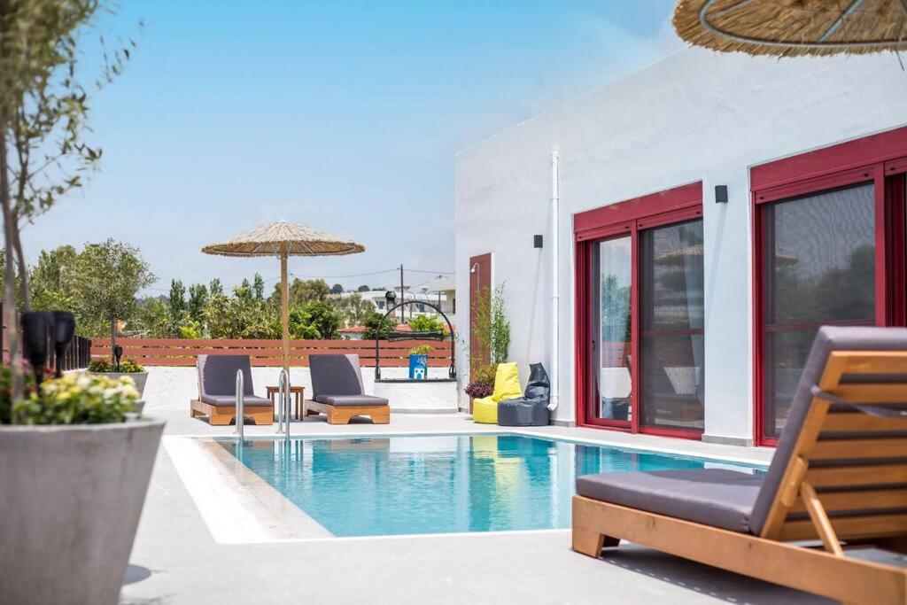 a pool with chairs and an umbrella next to a house at SunDaLucky in Afantou