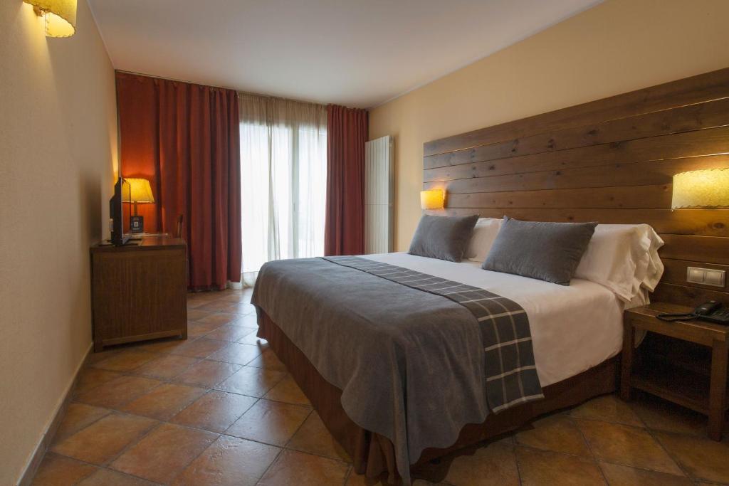 a bedroom with a large bed with a wooden headboard at Hotel Màgic Ski in La Massana