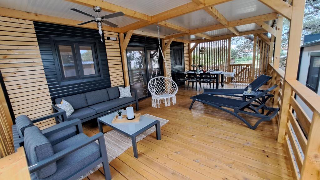 un porche cubierto con sofá y sillas en Premium mobile home Maslina - Oaza mira, en Drage