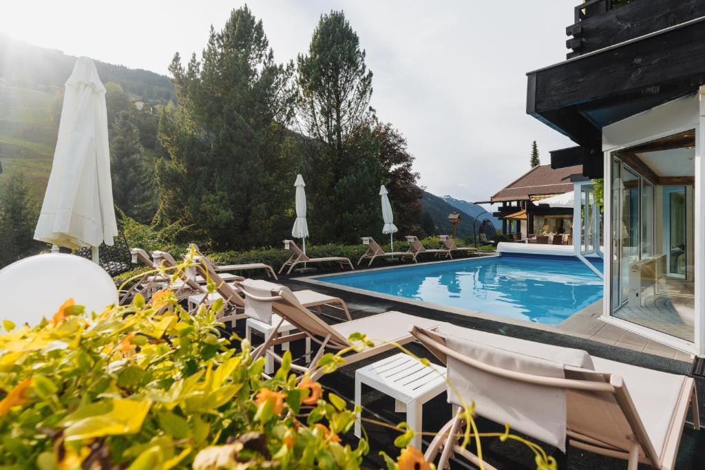 a resort with a swimming pool with chairs and umbrellas at Hotel Pfeifer in Gaschurn