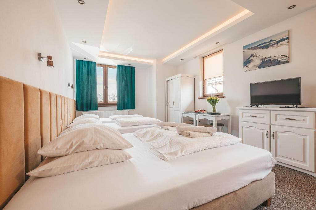 Dos camas en un dormitorio con cortinas verdes y un televisor. en Apartamenty u Semlów, en Szaflary
