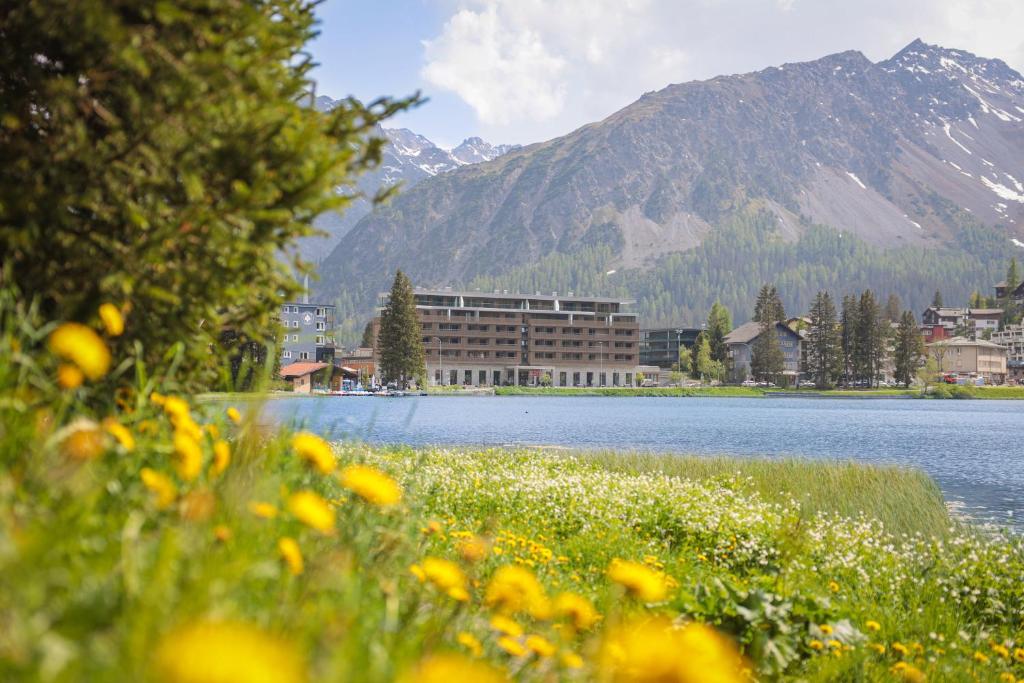a view of a lake with a building and mountains at AVES Hotel&amp;Apartment Arosa in Arosa