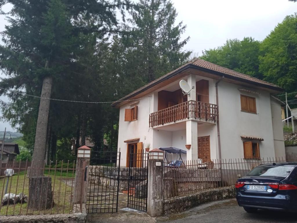 biały dom z balkonem i zaparkowanym przed budynkiem samochodem w obiekcie Villa Malgary w mieście Laceno