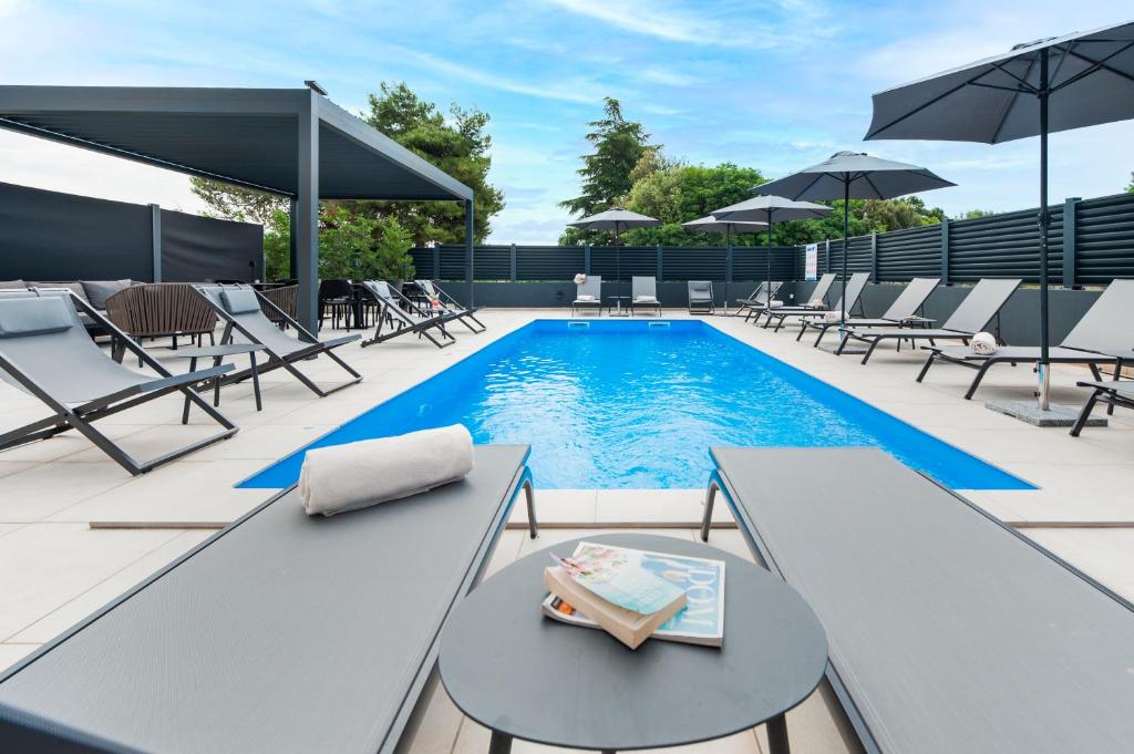 a swimming pool with lounge chairs and a table at Luxury Residence Levante in Rovinj