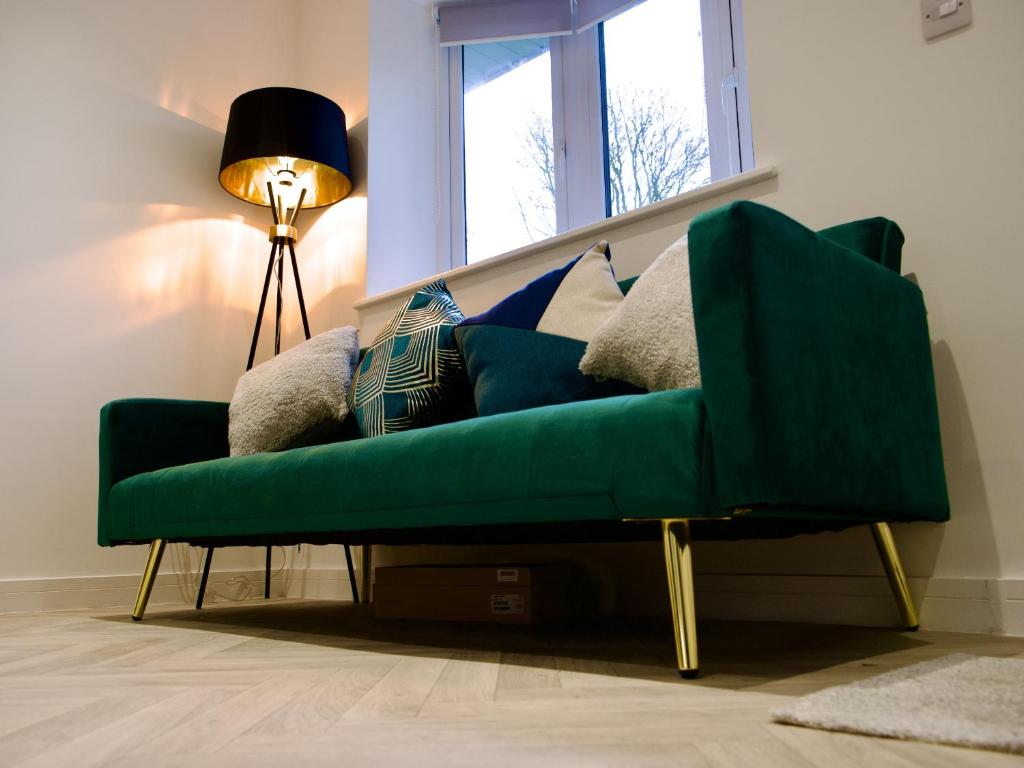 Ideal Lodgings in Radcliffe في رادكليف: أريكة خضراء في غرفة معيشة مع نافذة