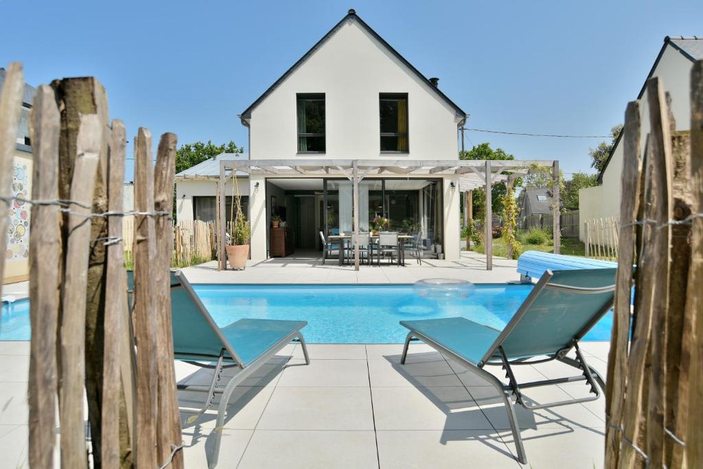 una casa con piscina y 2 sillas en Maison Gwenan - Maison contemporaine pour 8 proche plage, en Saint-Cast-le-Guildo