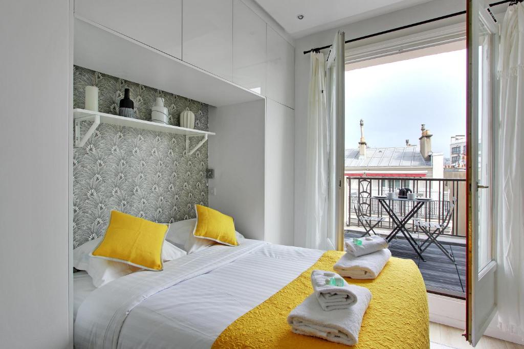パリにあるPick A Flat's Apartment in Madeleine - Boulevard de la Madeleineのベッドルーム1室(黄色い枕のベッド1台付)、バルコニーが備わります。