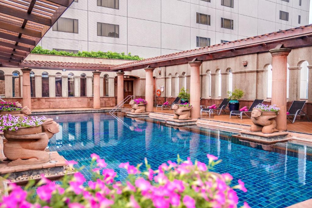 Crowne Plaza Bangkok Lumpini Park, an IHG Hotel في بانكوك: مسبح في مبنى فيه ورد وردي